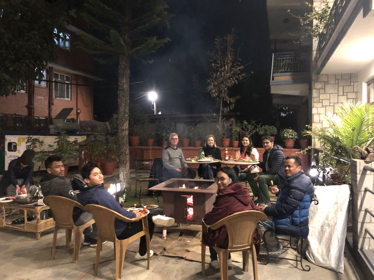 Guests and staff gathered around a fire pit on a winter evening on the terrace